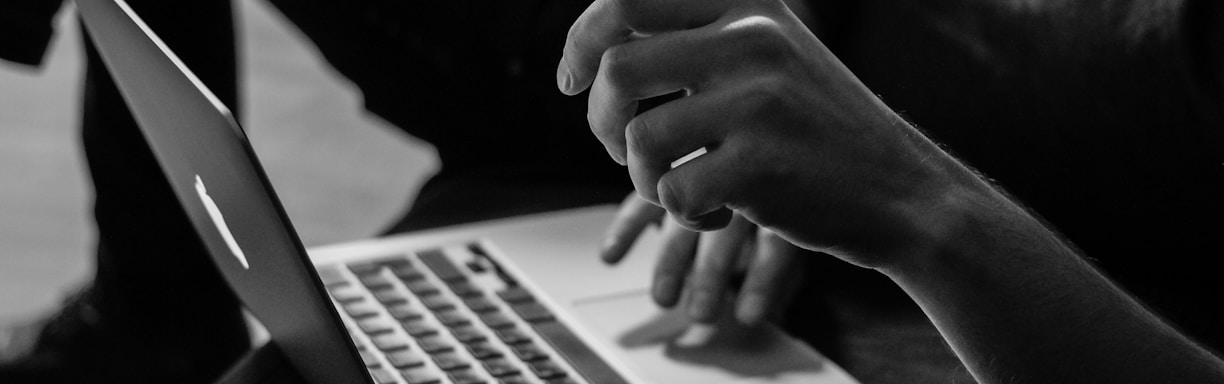 grayscale photo of person using MacBook