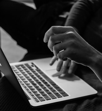 grayscale photo of person using MacBook