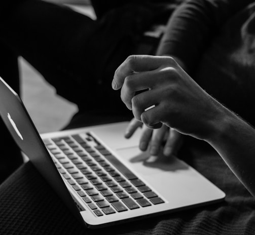 grayscale photo of person using MacBook