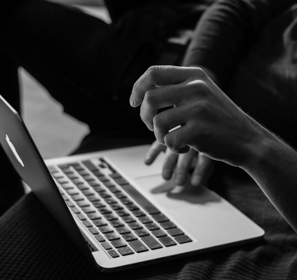 grayscale photo of person using MacBook