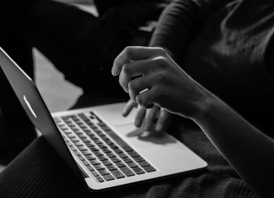 grayscale photo of person using MacBook