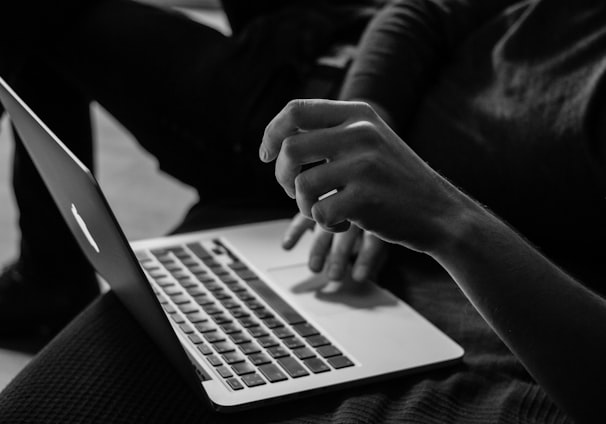 grayscale photo of person using MacBook