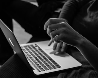 grayscale photo of person using MacBook