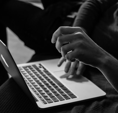 grayscale photo of person using MacBook