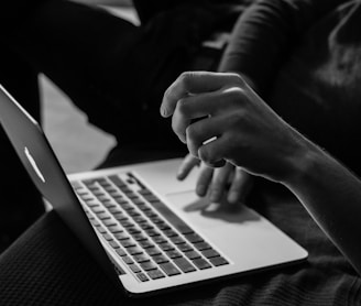 grayscale photo of person using MacBook