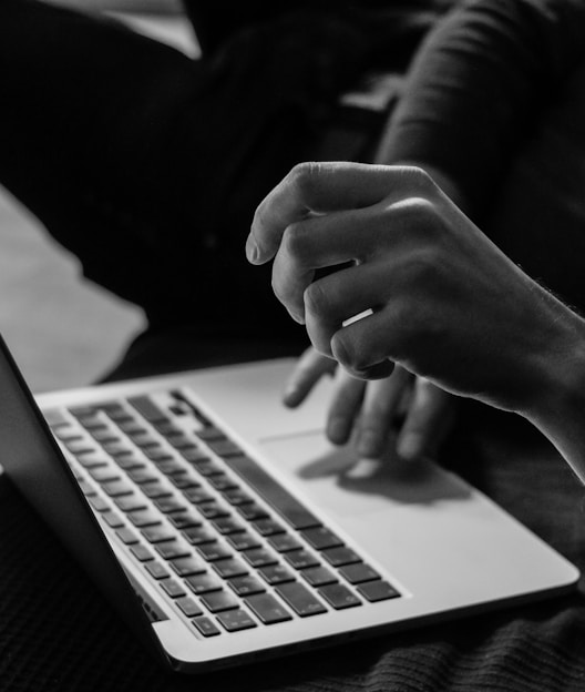 grayscale photo of person using MacBook