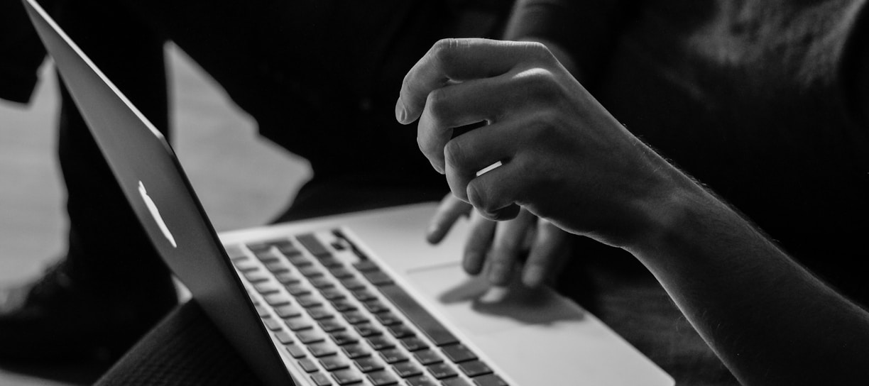 grayscale photo of person using MacBook