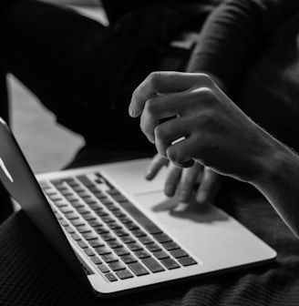 grayscale photo of person using MacBook