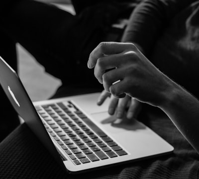 grayscale photo of person using MacBook