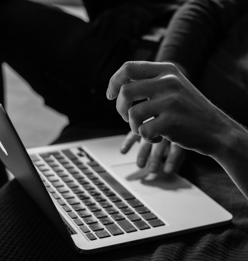 grayscale photo of person using MacBook