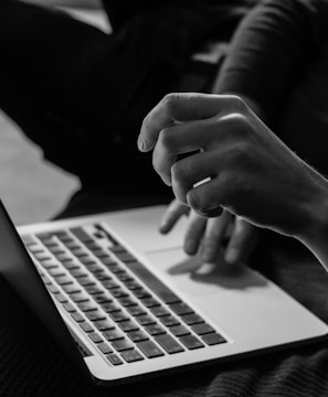 grayscale photo of person using MacBook