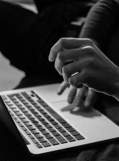 grayscale photo of person using MacBook