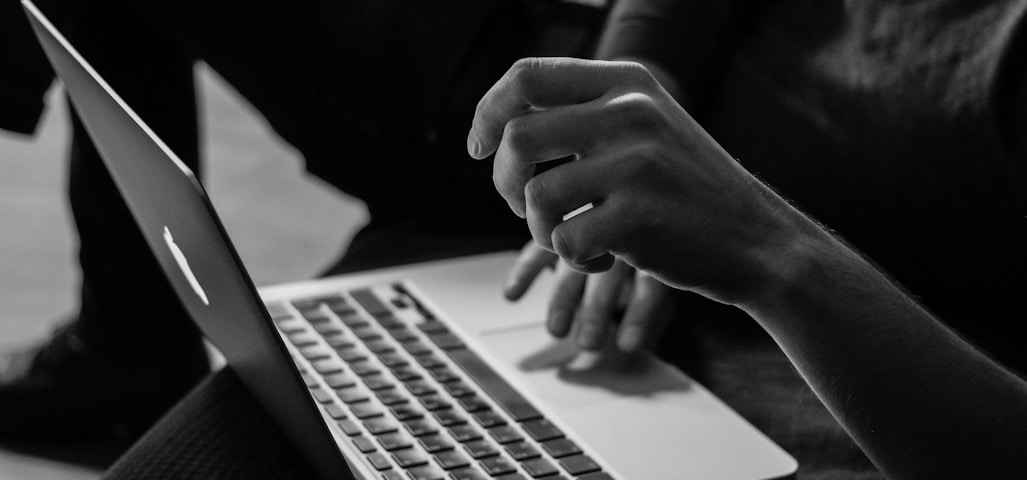 grayscale photo of person using MacBook