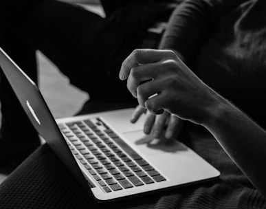 grayscale photo of person using MacBook