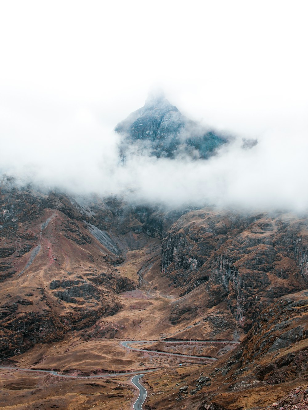 昼間の白い雲の下の山近くの灰色の道路の航空写真