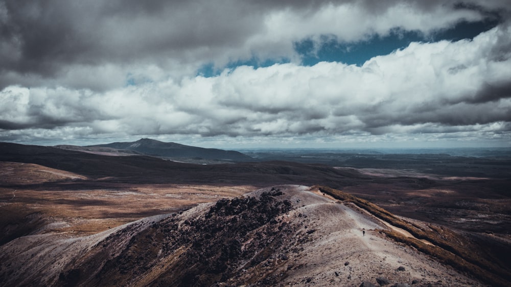 aerial photography of brown mountains with cloudy skies