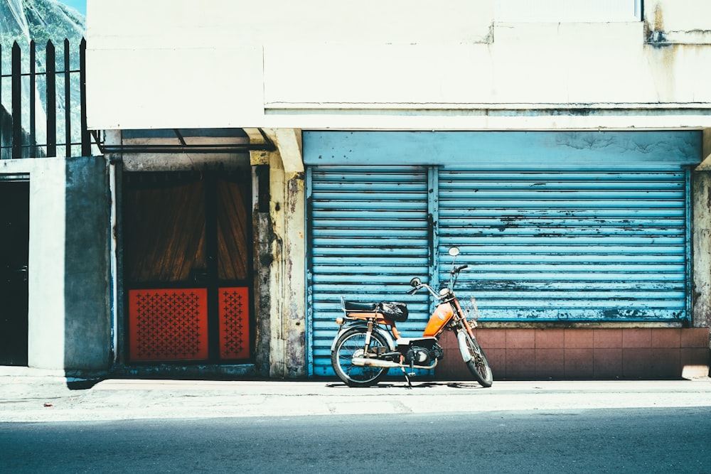 Motocicletta arancione vicino al cancello blu dell'otturatore