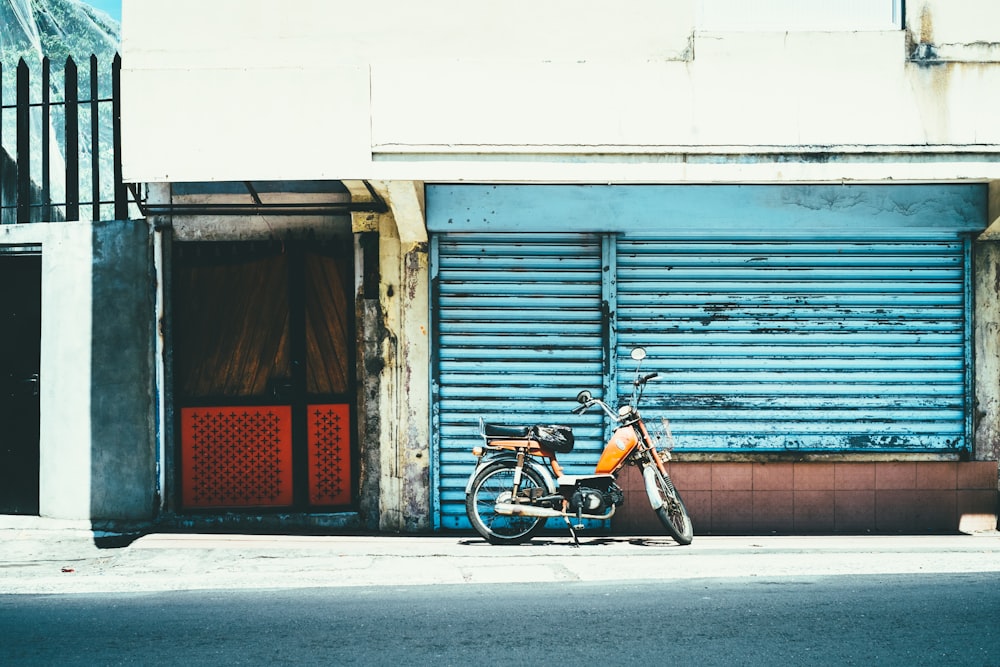 orange motorcycle near blue shutter gate