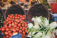 A vibrant food market stall with baskets of ripe tomatoes and herbs, bathed in natural light.
