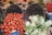 A vibrant market display featuring woven baskets full of fresh produce. Bright red tomatoes spill out of one basket, while another contains crisp white fennel bulbs. The scene is set against a backdrop of various vegetables, including carrots and greens.