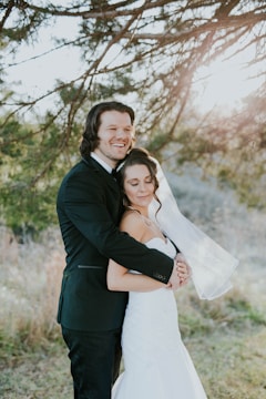 A bride and groom sharing a joyful embrace in a sunlit garden.