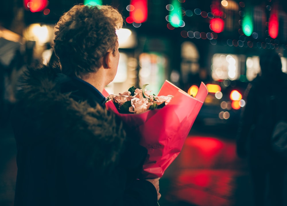 man in black faux fur coat holding bouquet of floweers