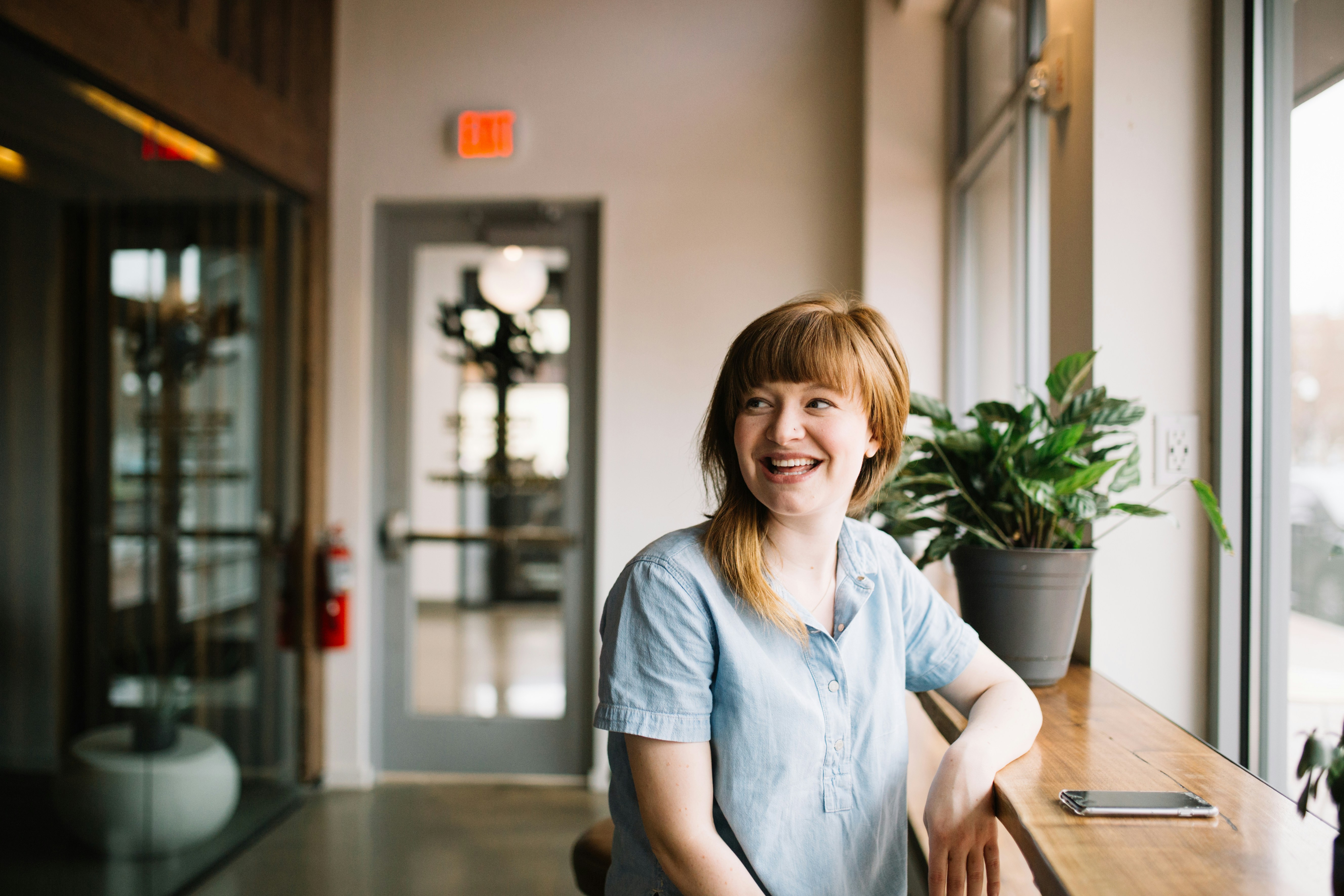 great photo recipe,how to photograph smiling woman by a window; woman sitting in front of brown wooden table