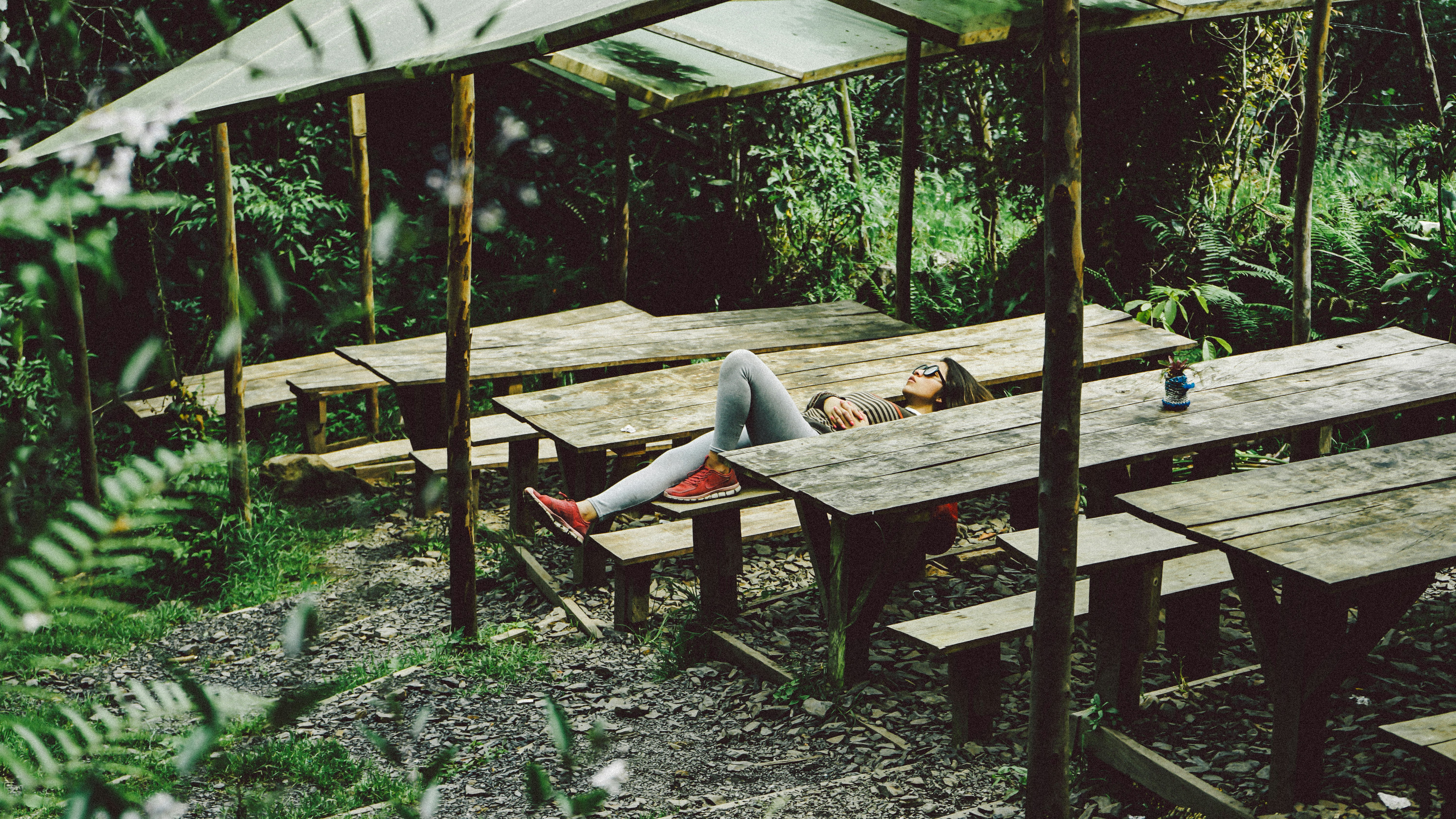 woman lying on gray wooden picnic table