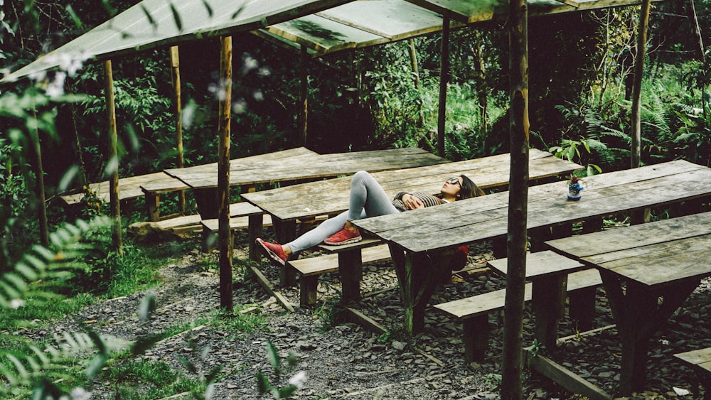 Frau liegt auf grauem Picknicktisch aus Holz
