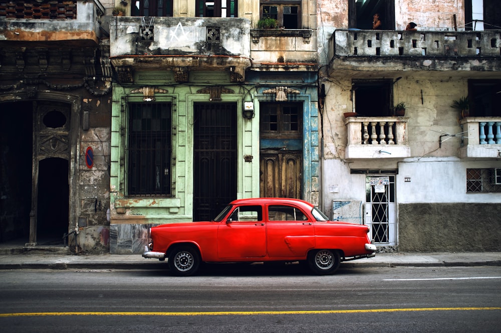 red car parked on road in front concrete building