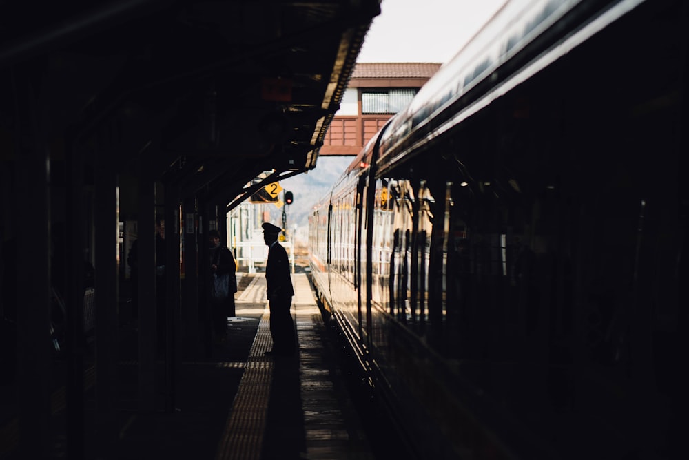 man standing near train in subway during daytime
