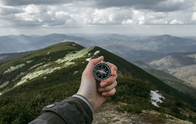 Close-up of hands holding a map with scenic mountain views in the background.