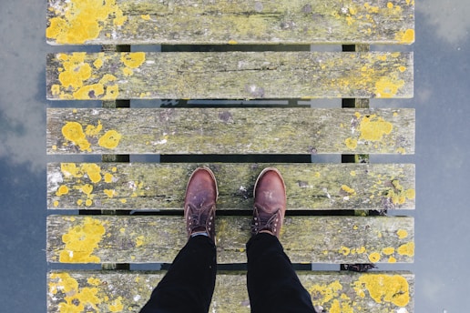 pair of brown leather shoes standing on grey and yellow bridge