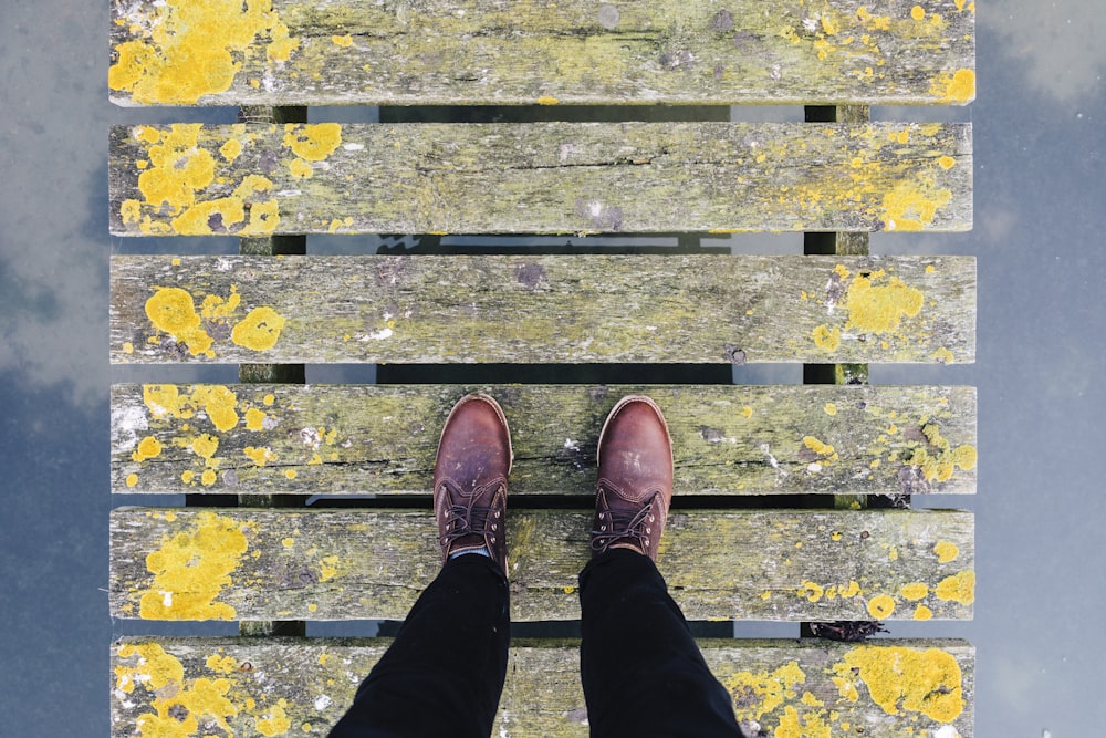 Par de zapatos de cuero marrón parados sobre puente gris y amarillo