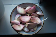 Close-up of fine, pale yellow dry garlic powder in a white ceramic bowl with a wooden spoon.