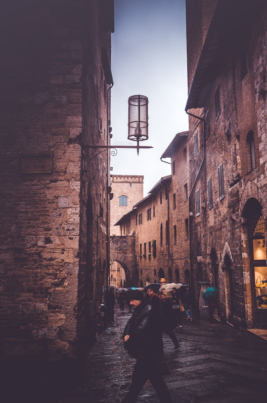 man wearing black jacket walking on alley in San Gimignano Italy