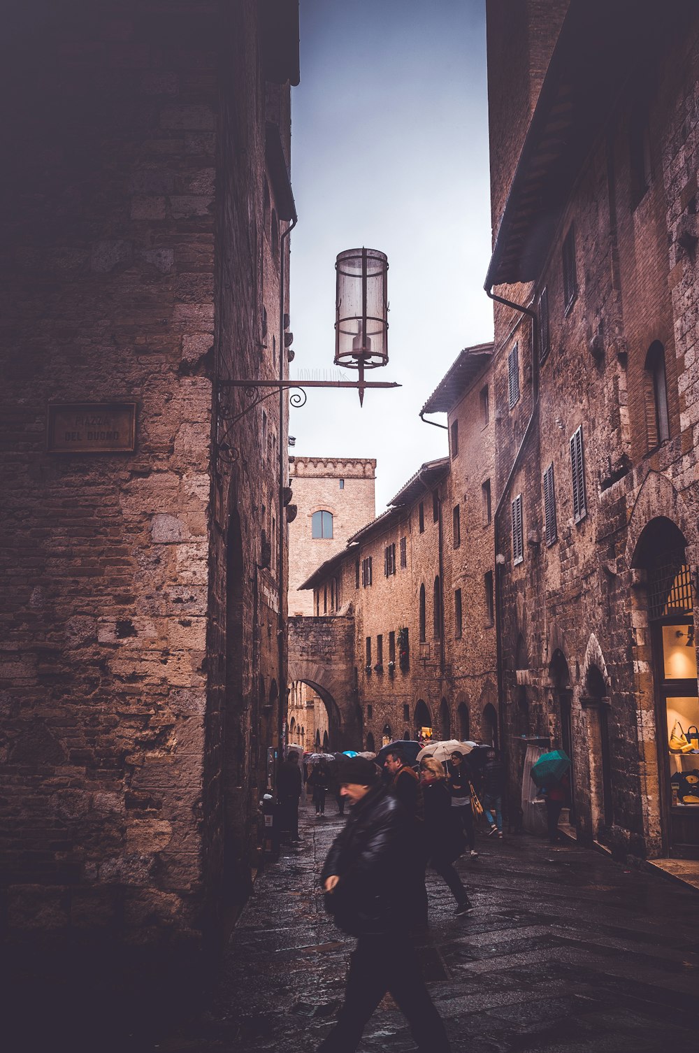 man wearing black jacket walking on alley