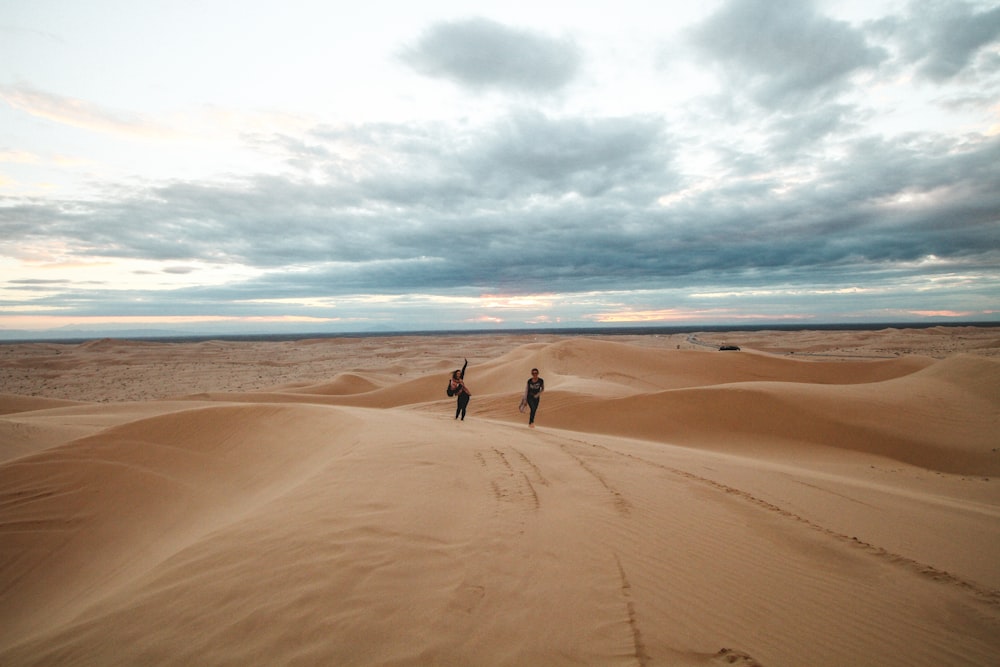 2 personnes marchant sur la plage de sable brun pendant la journée