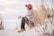 man sitting on sand with wheat looking right during daytime