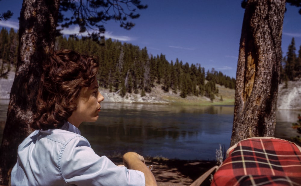 boy sitting near on lake under blue sky