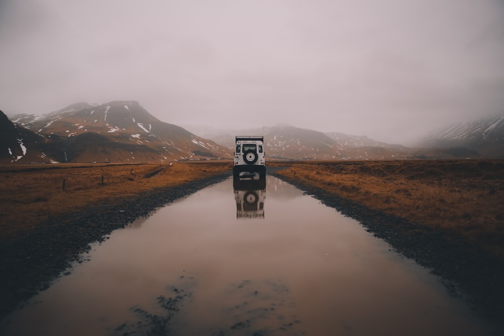 white and black vehicle on road with water during daytime