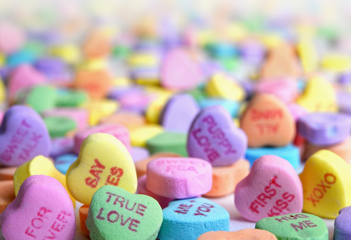 dulces con forma de corazón, de varios colores y frases para enamorados en el medio