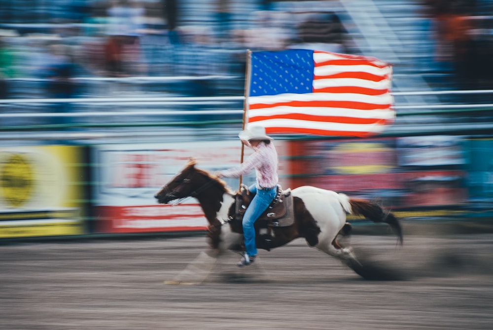 time lapse photo of man carrying U.S. flag while riding brown horse