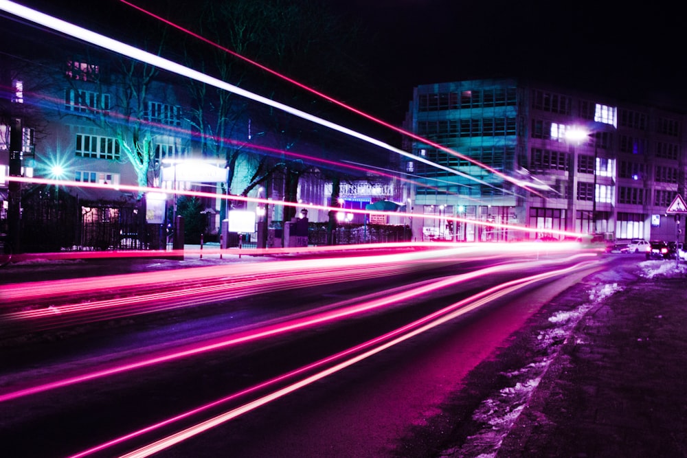 Zeitrafferfotografie von rosa Fahrzeuglichtern in der Nähe von Gebäuden