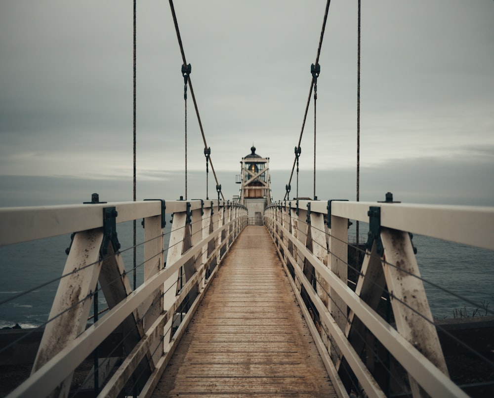 Brauner Leuchtturm aus Holz mit Brücke in der Nähe der Küste während des Tages