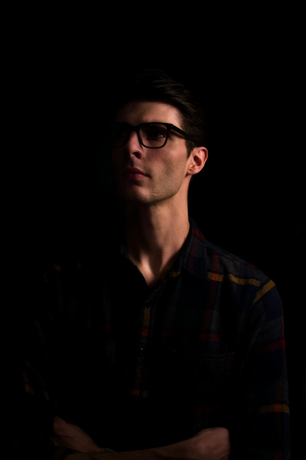a man with glasses standing in the dark