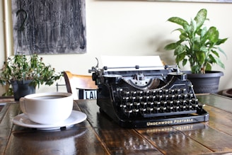An intimate workspace with a typewriter, scattered manuscript pages, and a steaming cup of coffee by a window.