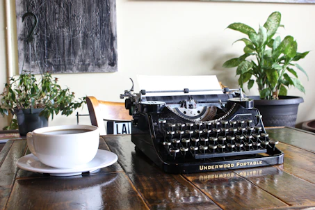 A cozy writing desk with a vintage typewriter and a steaming cup of coffee by a window.