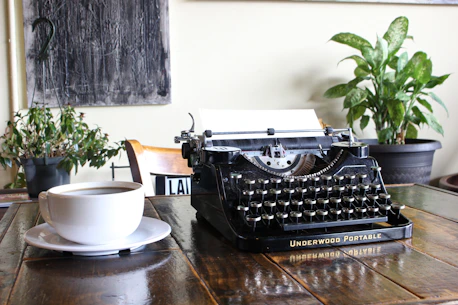 A cozy writing nook with a vintage typewriter and a steaming cup of coffee by the window.