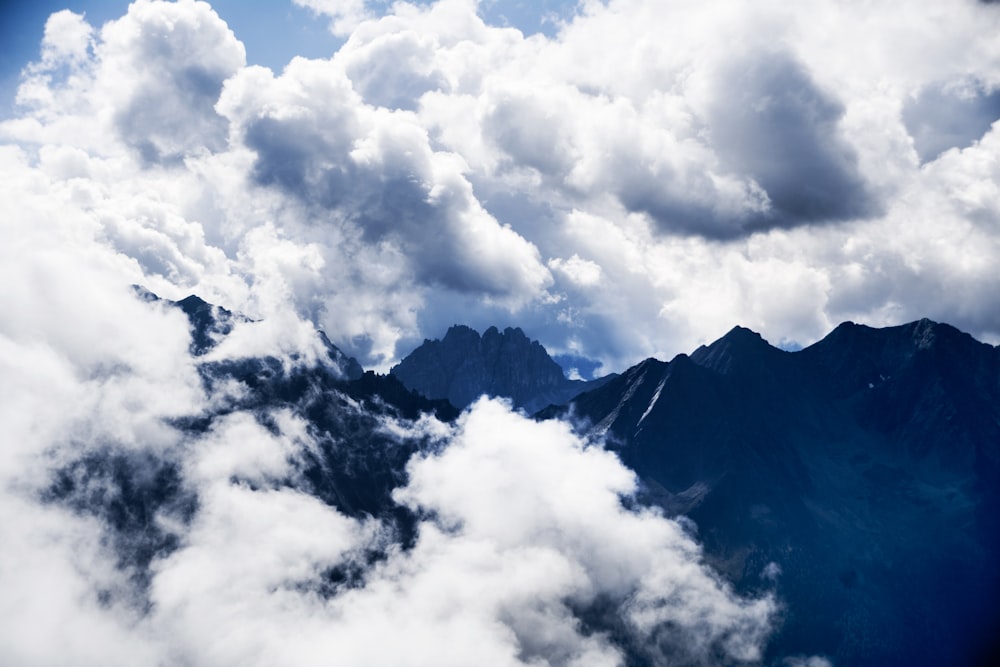 昼間の白い雲に覆われた山のシルエット